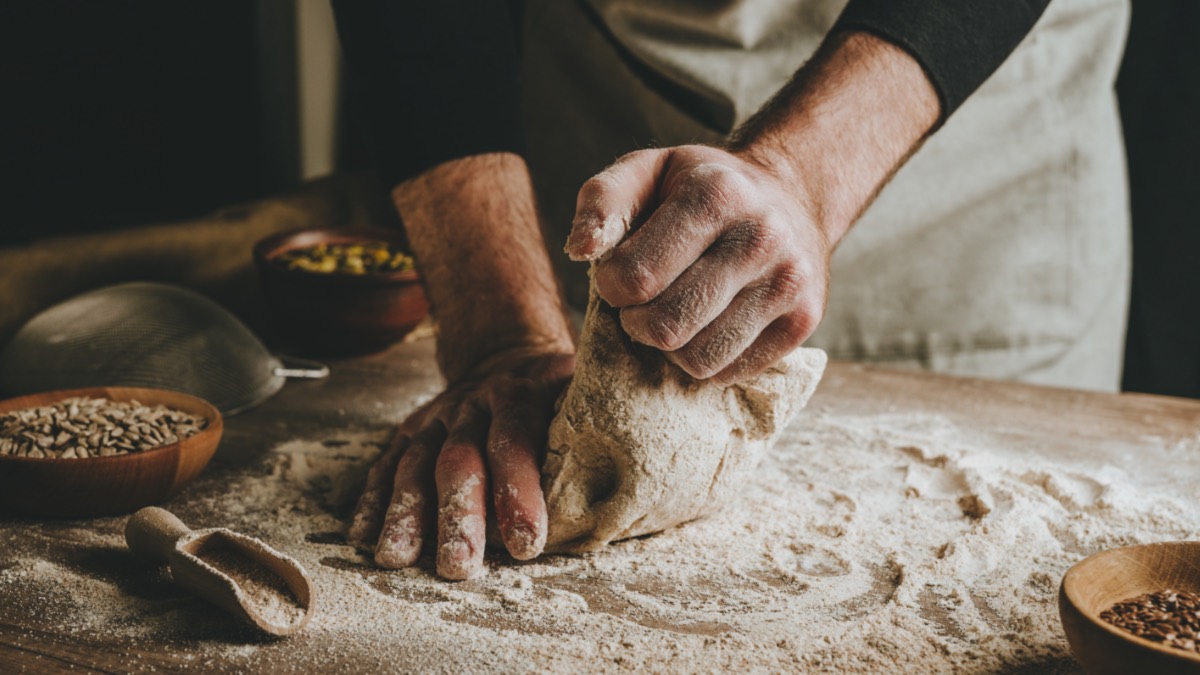 Ein Mann knetet Brotteig mit den Händen