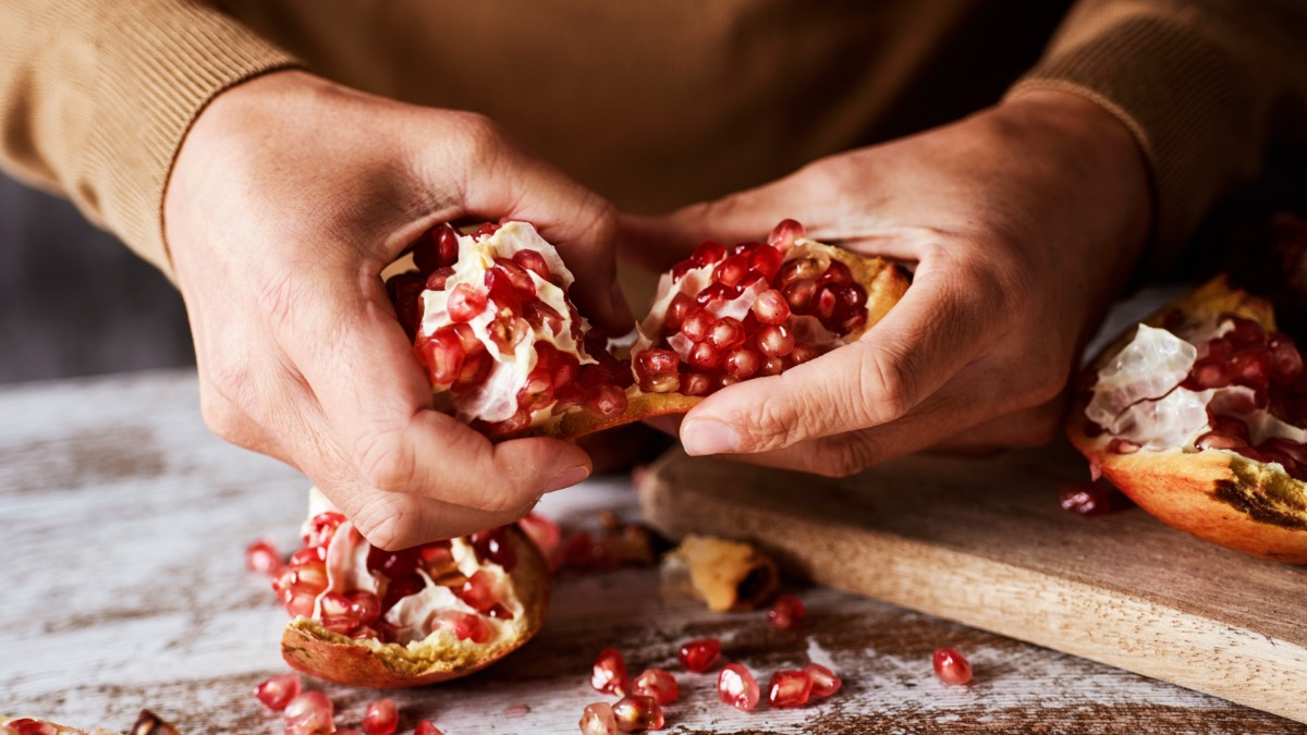 Ein Mann schält einen Granatapfel mit seinen Händen