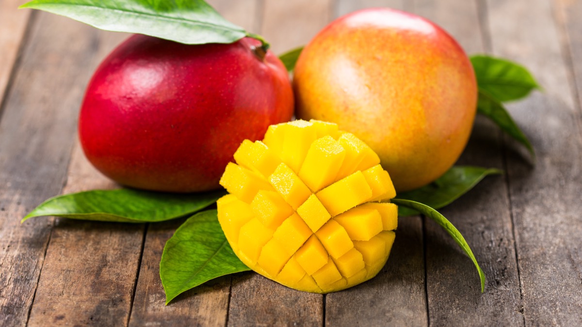 3 Mangos, ein davon aufgeschnitten und gewürfelt