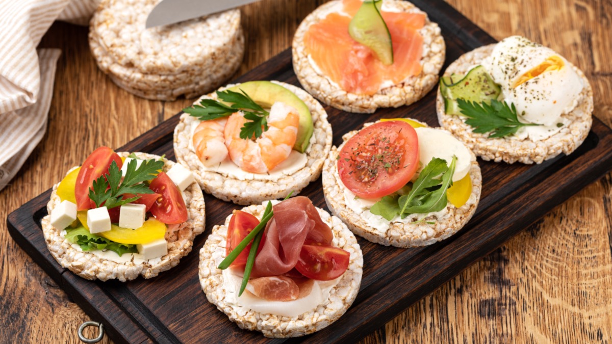 6 Reisewaffeln mit Frischkäse und verschiedenen Belägen auf Holzbrett