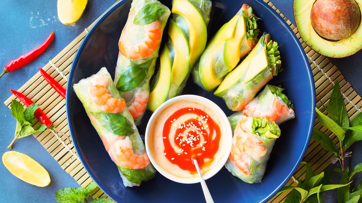 7 unterschiedlich gefüllte Sommerrollen auf blauem Teller mit Dip
