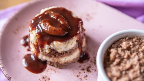 Zweifarbiger Grießflammeri mit Pflaumenmus und einer halben Pflaume auf einem lilafarbenen Teller. Rechts davon steht ein Schälchen mit einem weiteren, noch nicht gestürzten Grieflammeri.