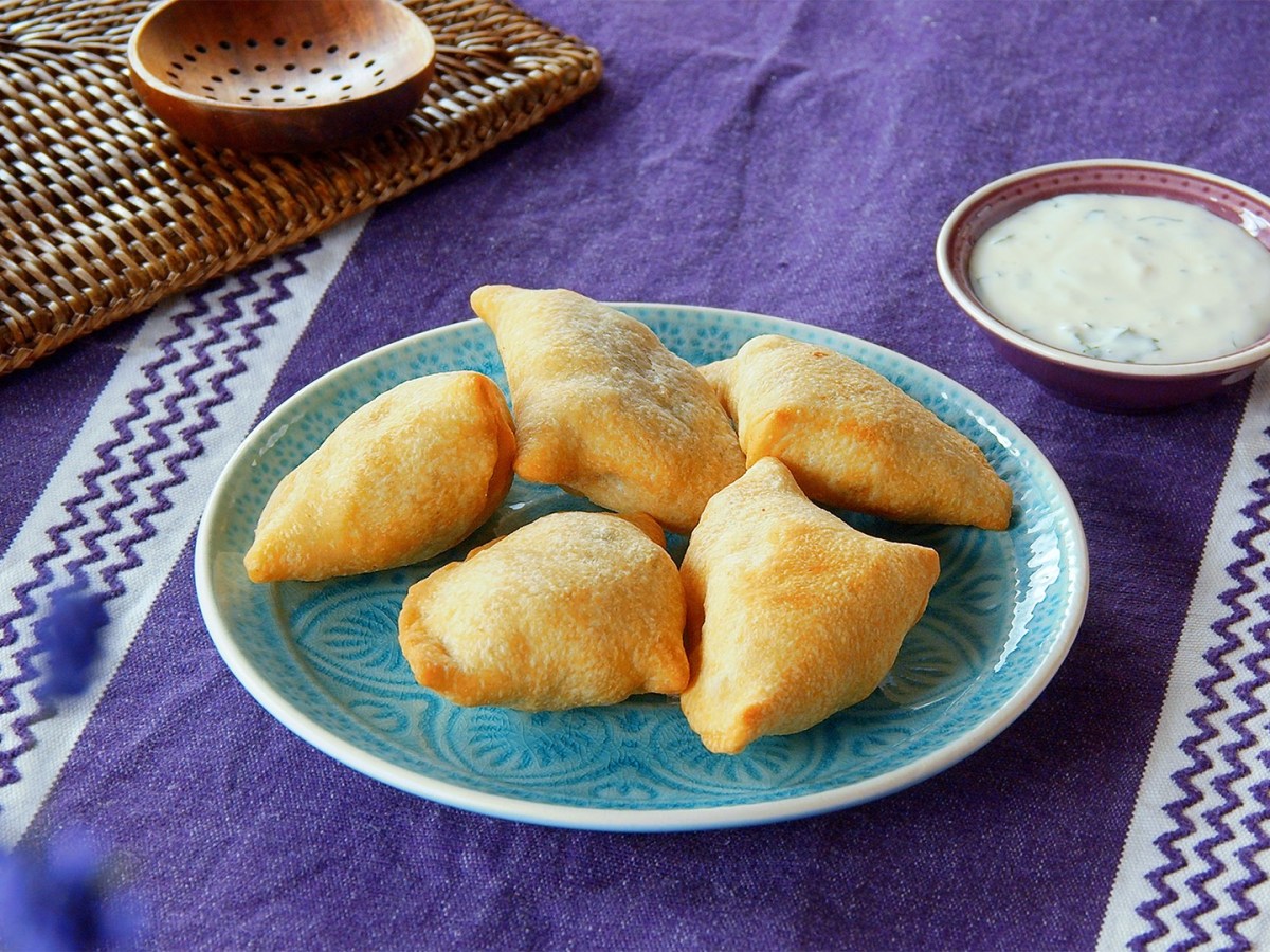 Ein Teller mit Samosas, drumherim Zutaten.