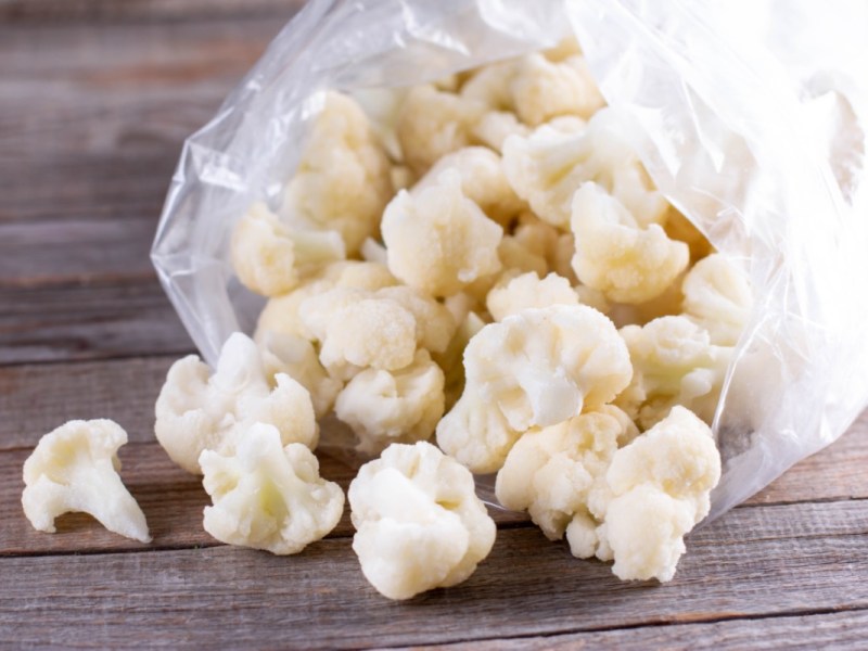 Eingefrorener Blumenkohl, der aus einer Plastiktüte herauskullert.