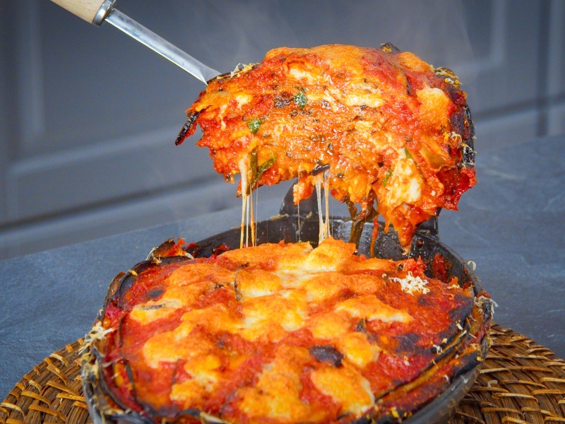 Parmigiana in einer Auflaufform, überbacken mit Mozzarella und Parmesan.