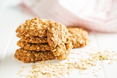 Ein Stapel Bananen-Haferflocken-Kekse, drumherum Haferflocken, Nahaufnahme.