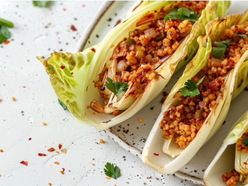Chicoree-Tacos mit Couscous-Füllung auf hellem Hintergrund.
