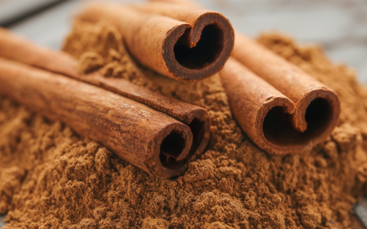 Jeden Tag Zimt essen: Einige Zimtrollen liegen auf einem Berg Zimtpulver.