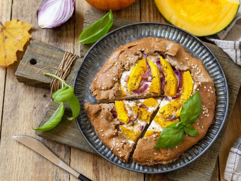Eine Kürbis-Galette mit Ricotta auf einem Brett.