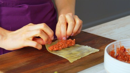 Eine Köchin rollt Hackfleischfüllung in ein blanchiertes Kohlblatt ein.