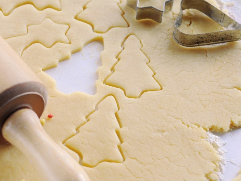 Tipps fürs Plätzchenbacken: ausgerollter Plätzchenteig mit Nudelholz und Ausstechförmchen.