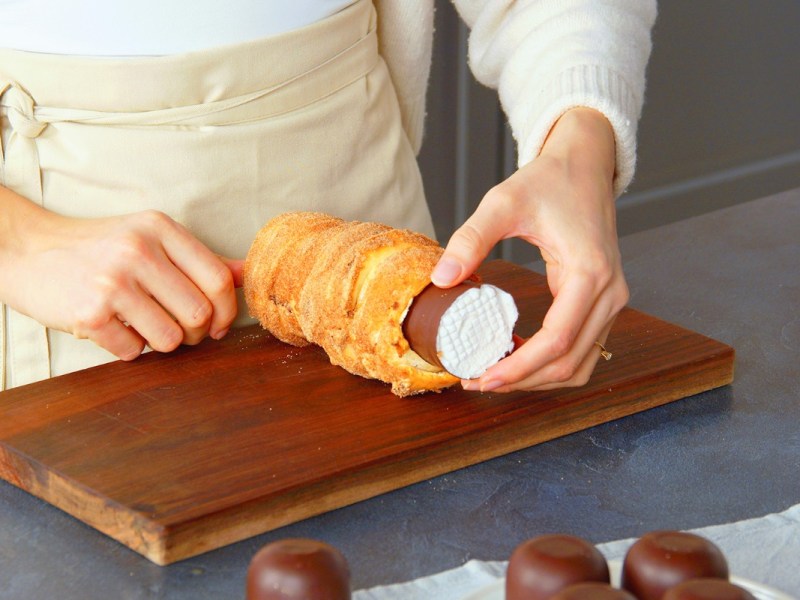 Eine Köchin füllt einen Baumstriezel mit einer Schaumkussfüllung.