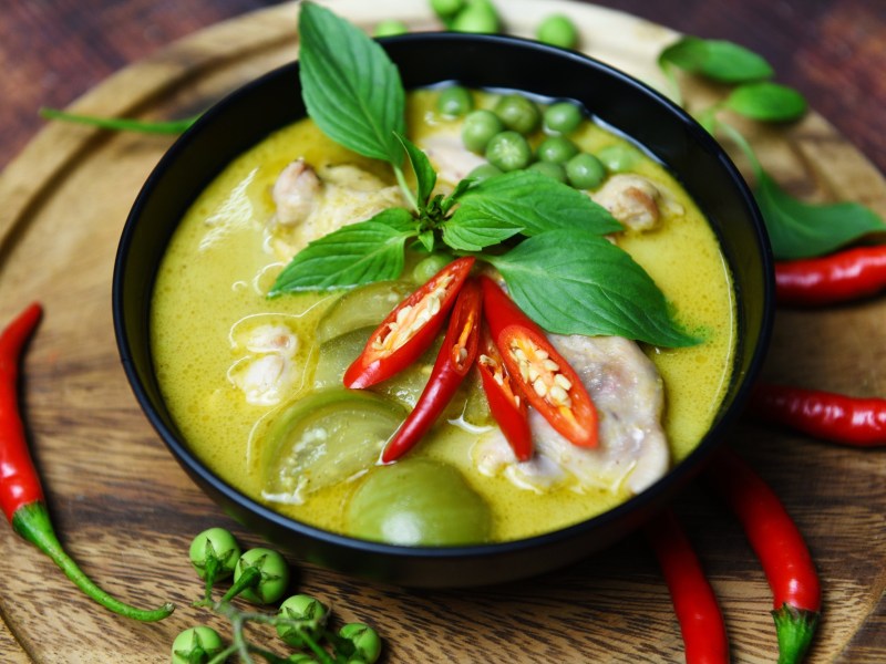 Grünes Kokosnuss-Curry in einer Schale, garniert mit Chili.