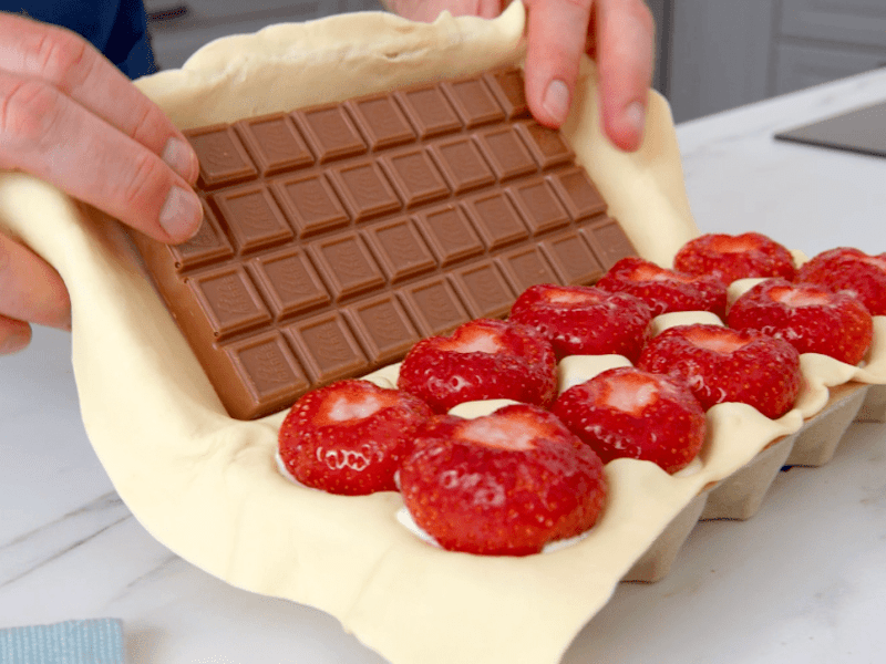Top-10-Rezepte 2024: Ein KOche klappt einen Eierkarton zu, in dem Erdbeeren und Schokolade liegen.