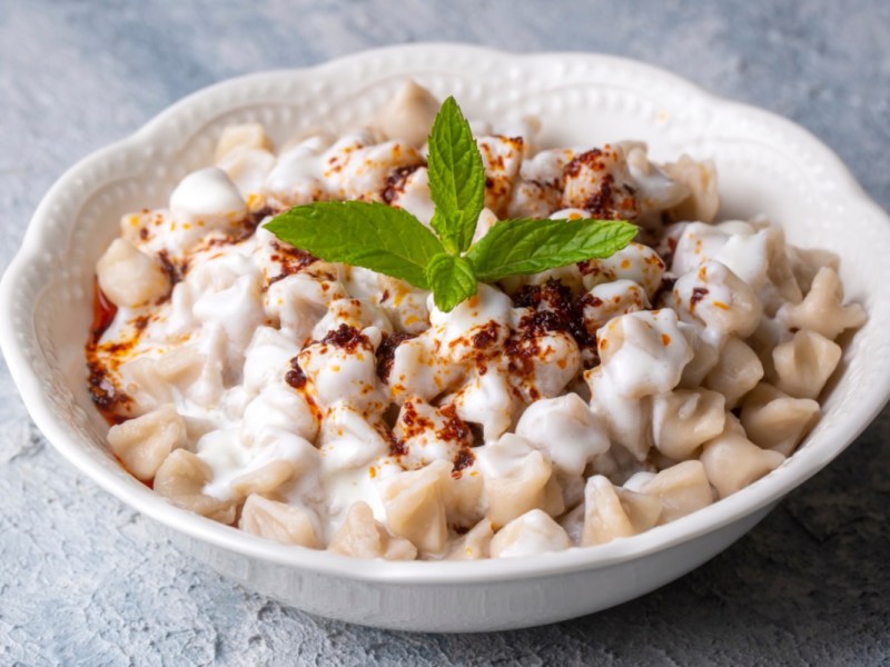 Türkische Manti mit Joghurtsoße auf einem Teller.