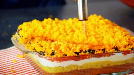 Seven-Layer-Dip: ein Koch schmilzt Cheddar mit einem Brenner.