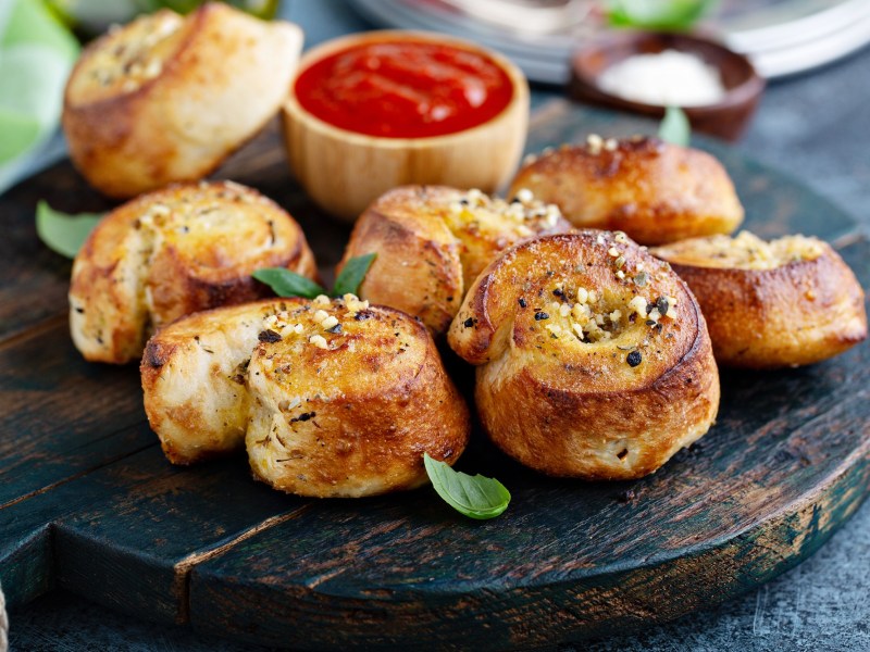 Knoblauchschnecken auf einm dunklen Holzbrett. serviert mit Tomatendip.