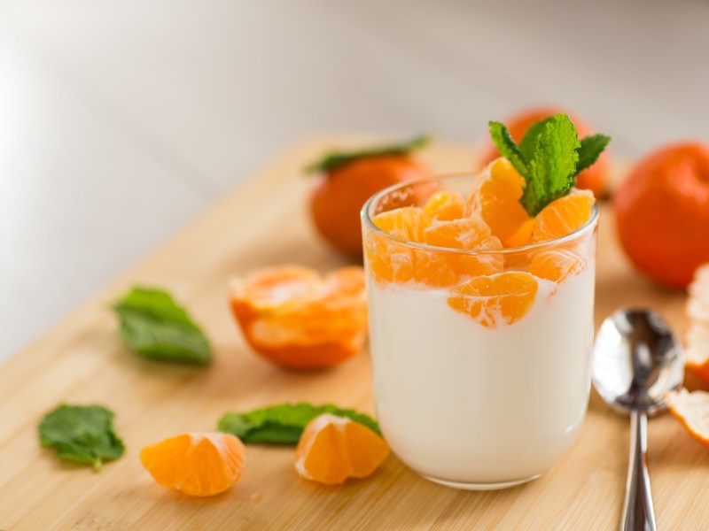 Glas mit Mandarinenquark und Mandarinen daneben