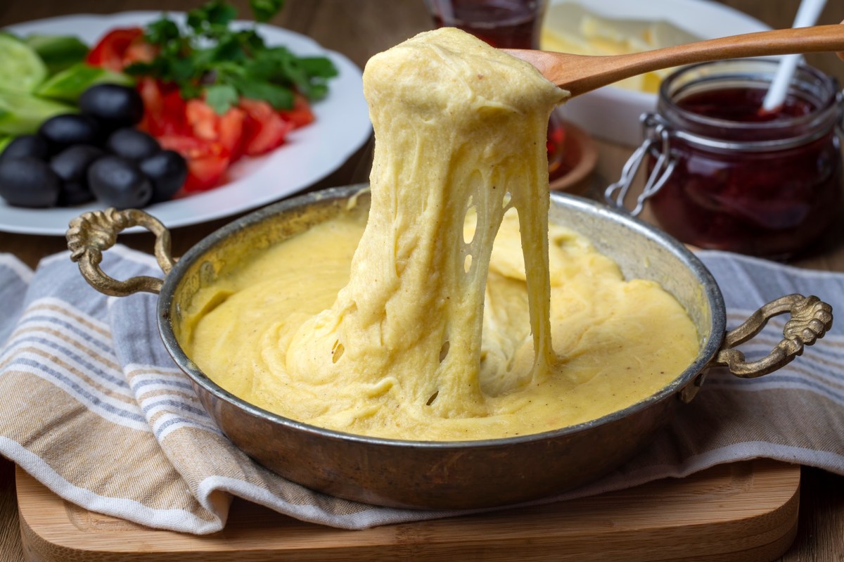 Ein Topf mit Mıhlama: türkisches Käsefondue. Ein Löffel zieht etwas von dem Fondue nach oben.