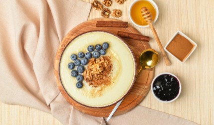 Eine Schüssel Polenta-Grießbrei mit Heidelbeeren, Walnüssen und Zimt in der Schüssel in der Draufsicht.