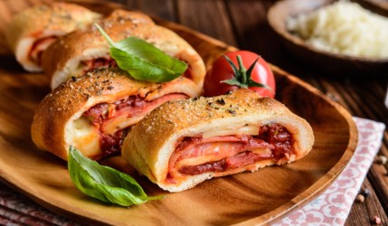 Stromboli Pizza mit Salami und Käse auf einem Holztablett.