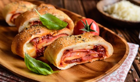 Stromboli Pizza mit Salami und Käse auf einem Holztablett.