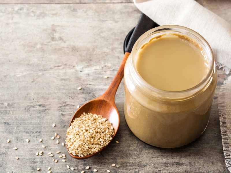 Tahini selbst machen: ein Glas Tahini mit Sesamsaat daneben.