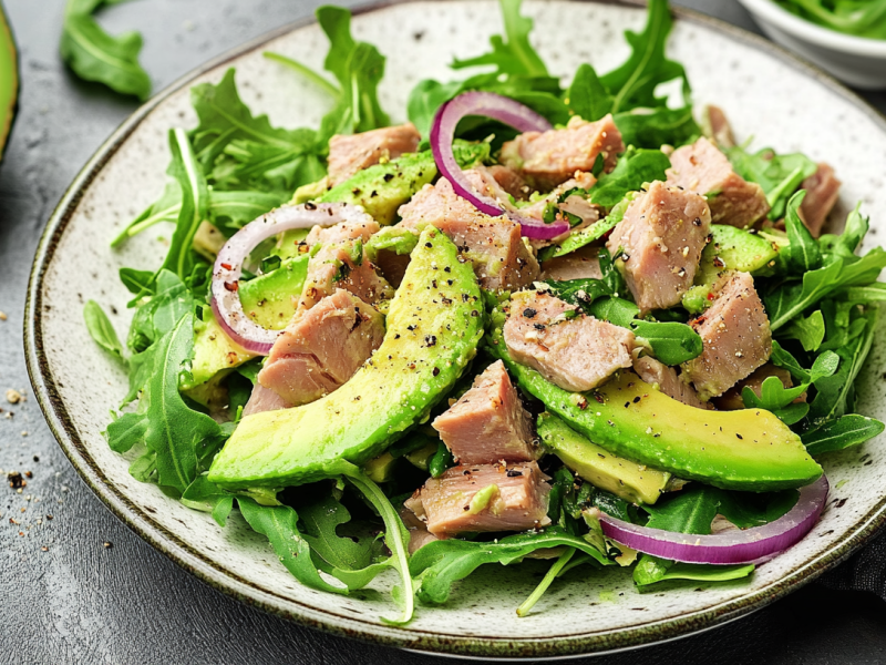 Avocado-Thunfisch-Salat auf einem hellen Teller, garniert mit schwarzem Pfeffer.