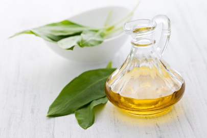 Eine Flasche Bärlauchöl, daneben einige Bärlauchblätter.