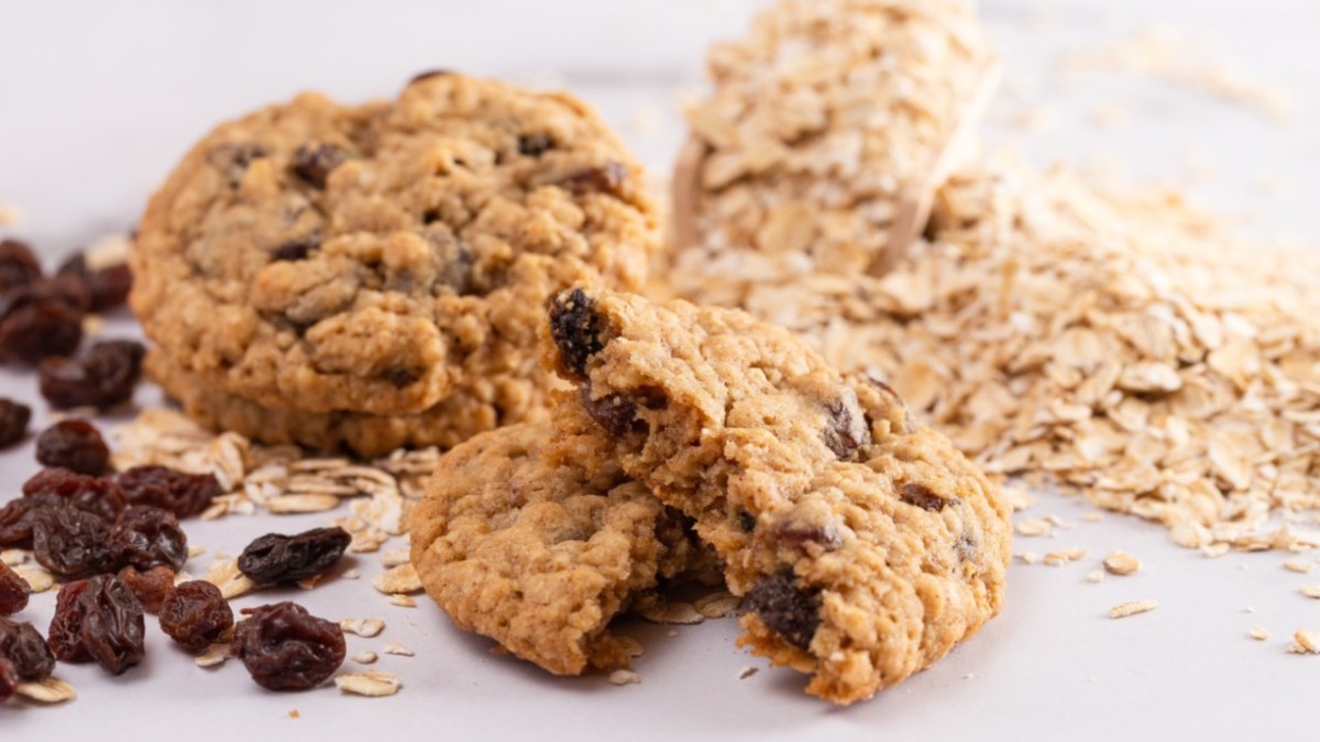 Mehrere zuckerfeie Haferflockenkekse mit Joghurt und Rosinen. Daneben finden sich Zutaten.