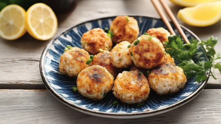 Mehrere isländische Fischbällchen auf einem Teller. Daneben liegen halbierte Zitronen und Essstäbchen.