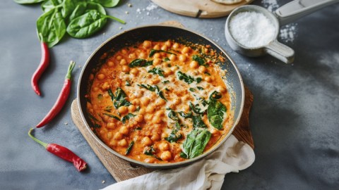 Ein Kichererbseneintopf mit Harissa in der Draufsicht. Drumherum frische Zutaten.