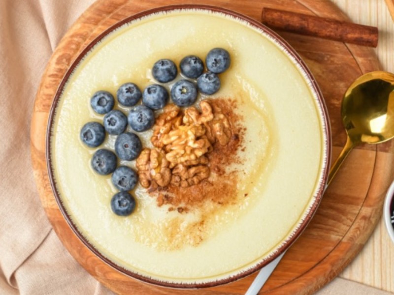 Eine Schüssel Polenta-Grießbrei mit Heidelbeeren, Walnüssen und Zimt in der Schüssel in der Draufsicht.