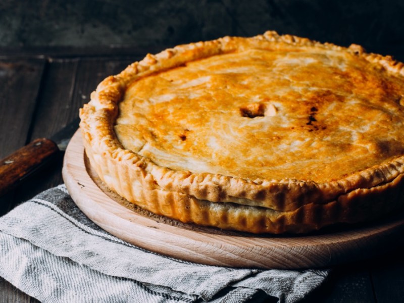 Ein Rindfleisch-Pie auf einem runden Holzbrett.