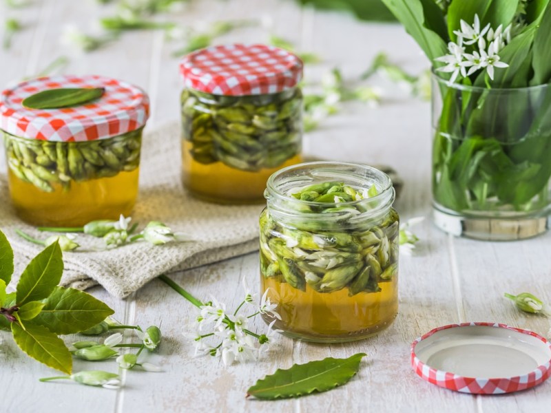 Gläser mit Bärlauch-Kapern und Bärlauch auf einem Tisch