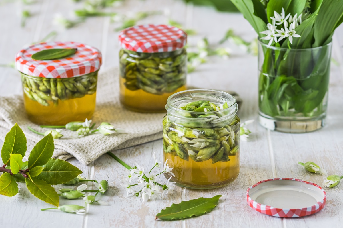 Gläser mit Bärlauch-Kapern und Bärlauch auf einem Tisch