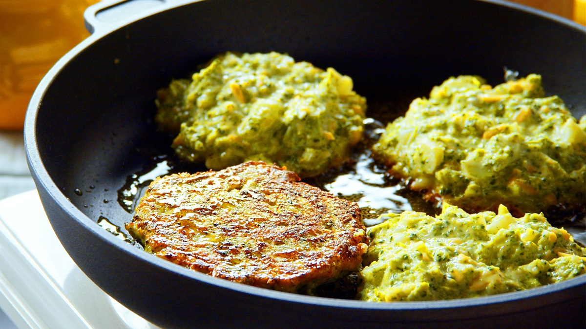 Vier Brokkoli-Bratlinge in einer Pfanne.