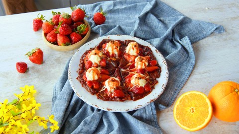 Ein Teller mit Erdbeer-Crêpes mit grünem Pfeffer, darauf mehrere Kugeln Vanilleeis.