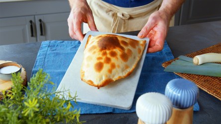 Eine Flammkuchentasche wird auf einem Brett präsentiert.