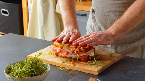 Ein Koch präsentiert ein aufgeschnittenes gefülltes Pizzabrot.