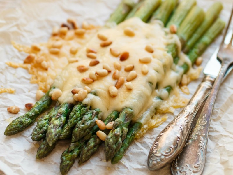 Grüner Spargel mit Käse und gerösteten Pinienkernen.