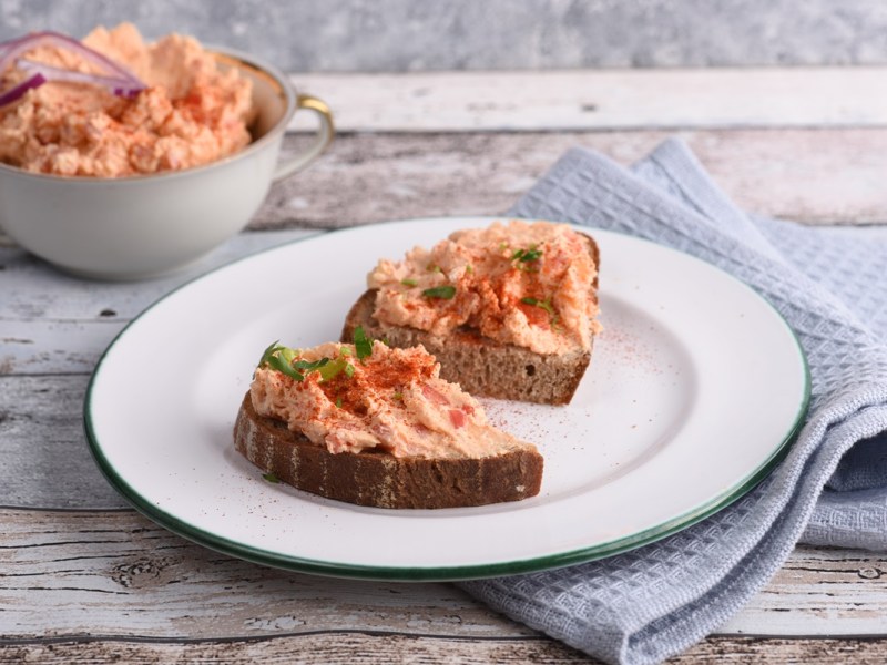 Eine Stulle mit Liptauer Aufstrich, eine Schale mit dem Aufstrich daneben