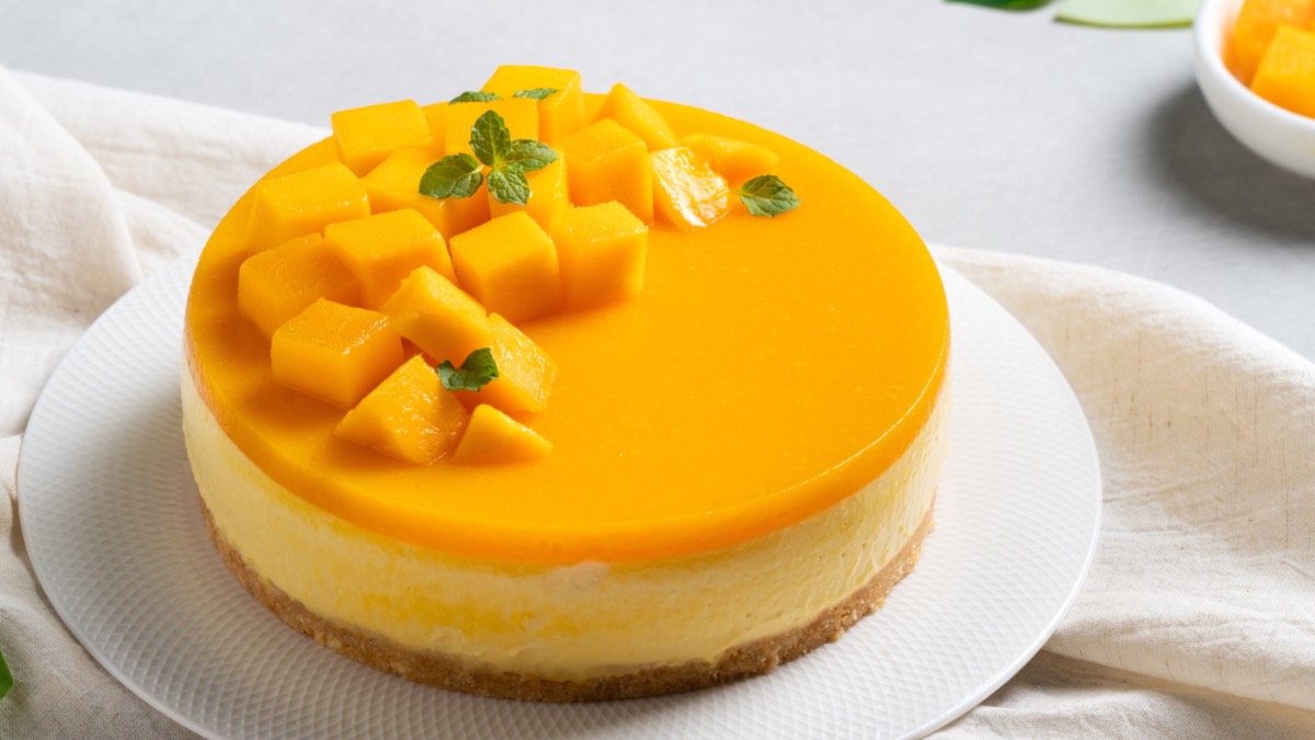 Ein Mango-Käsekuchen auf einer runden Kuchenplatte.