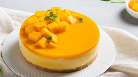 Ein Mango-Käsekuchen auf einer runden Kuchenplatte.