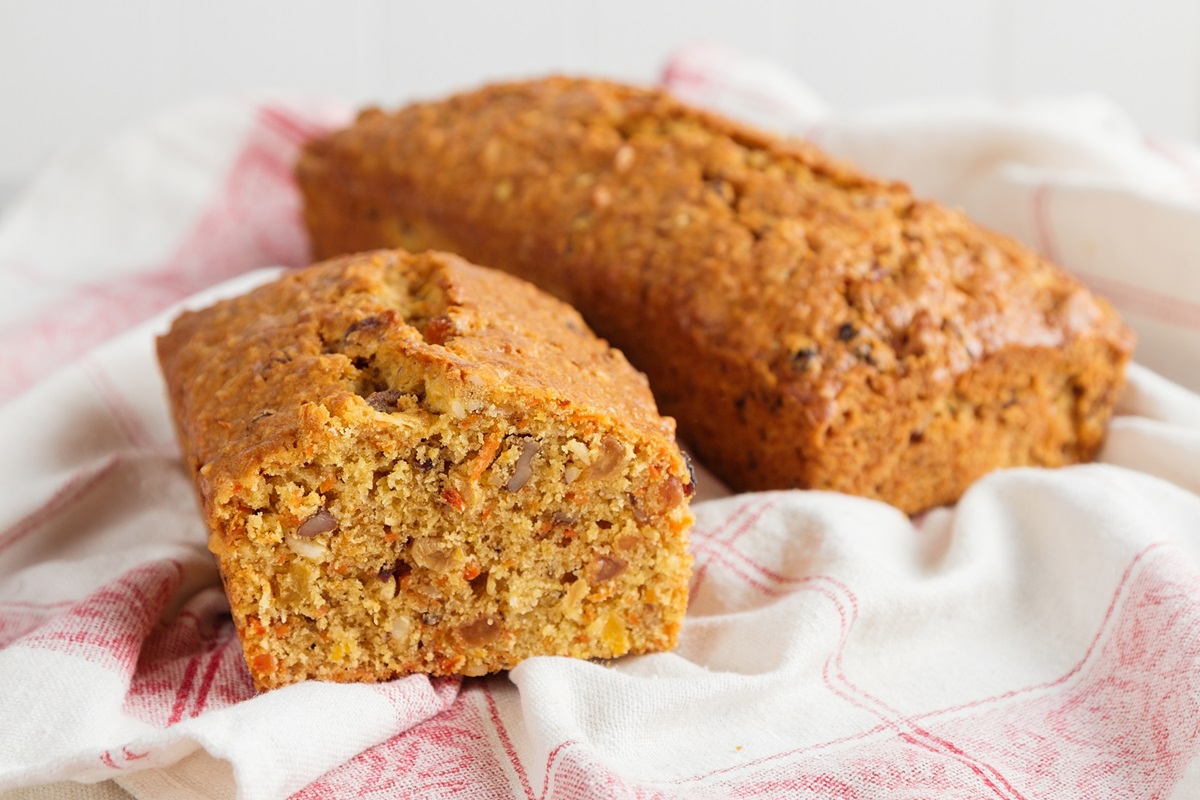 Zwei Laibe Möhren-Apfel-Kuchen ohne Zucker auf einem rot-weißen Geschirrtuch.