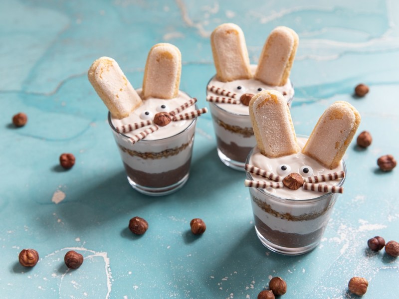 Einige Gläser Osterhasen-Tiramisu auf einem blauen Tisch.