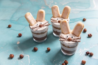 Einige Gläser Osterhasen-Tiramisu auf einem blauen Tisch.