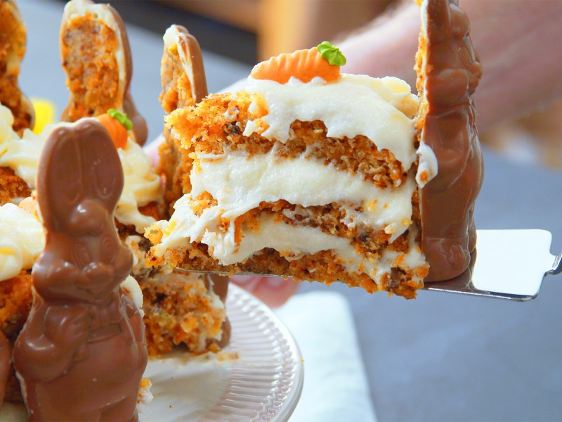 Ein Kochen eninimmt ein Stück Osterhasen-Torte mit Schokohasen.