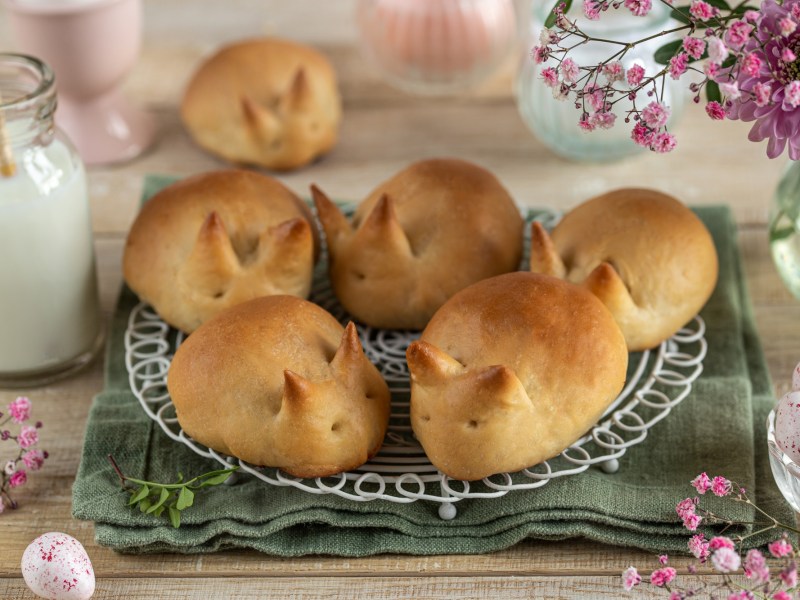 Osterhasen-Zitronenbrötchen auf einem Kuchengitter, drumherum Osterdeko.