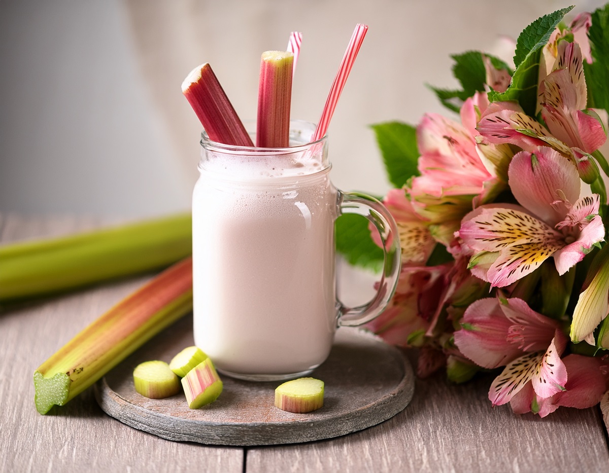 Glas mit Rhabarber-Lassi und Rhabarberstangen auf einem Tisch